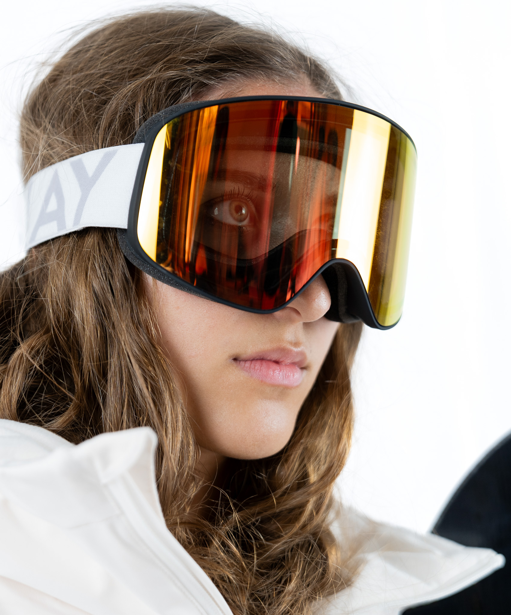 A model wearing IconPro ski goggles, part of the Best Gifts for Skiers selection: gifts for her. The goggles feature a sleek design with a white strap and gold lens, highlighting their stylish and functional aspects.